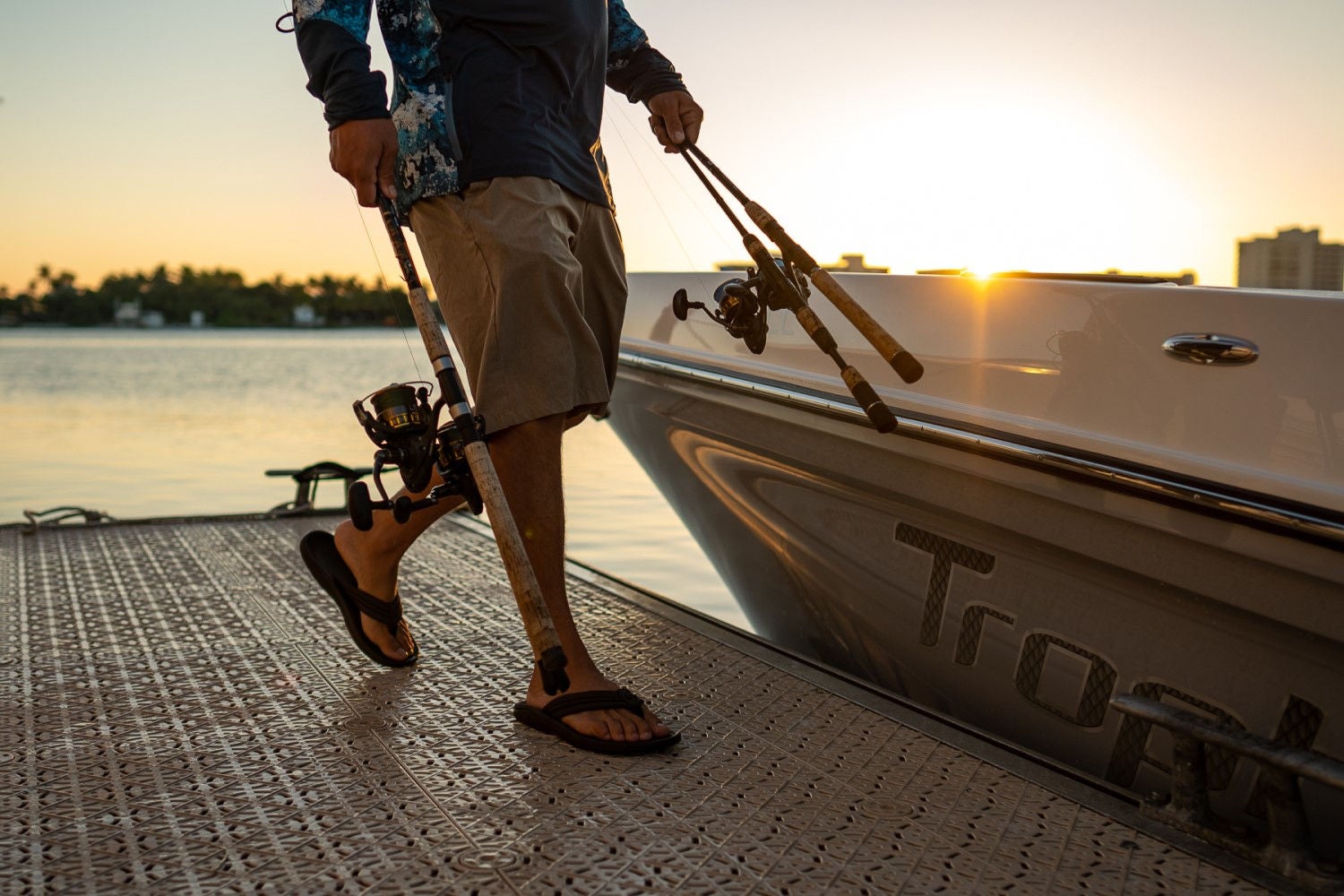 man loading fishing poles onto the Trophy T24CC fishing boat
