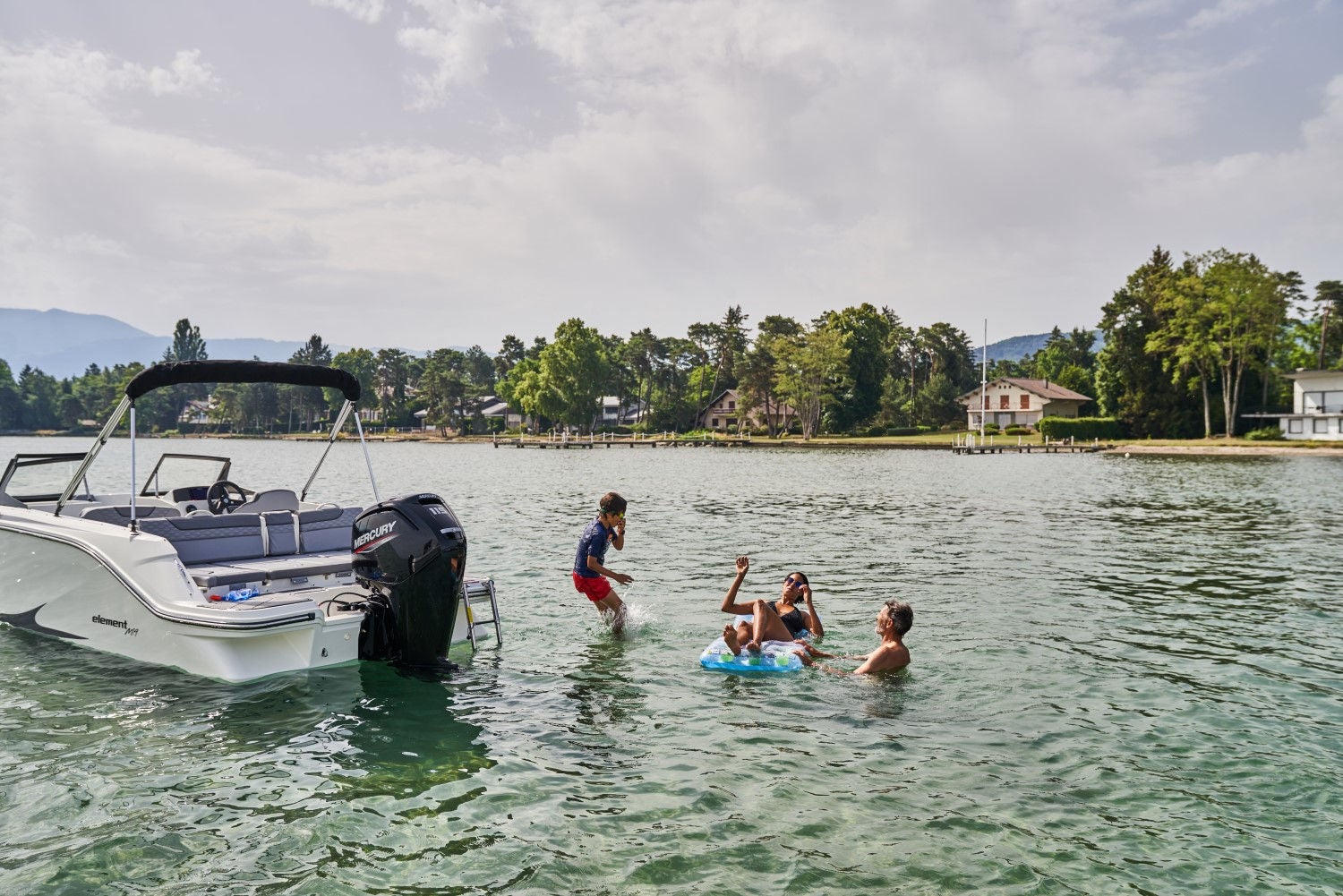 family swimming off the back of a while Element M19 deck boat