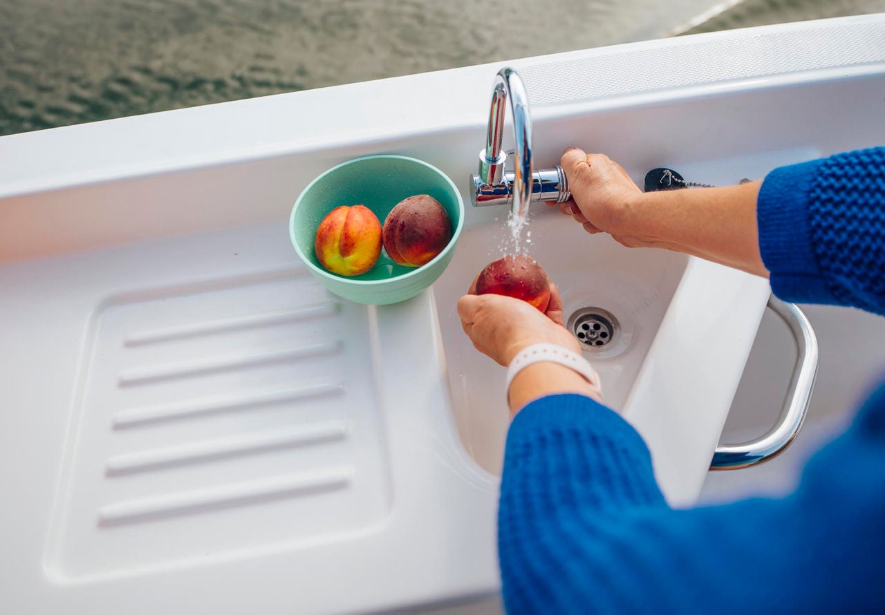 person washing fruit in the onboard sink on a D22 deck boat