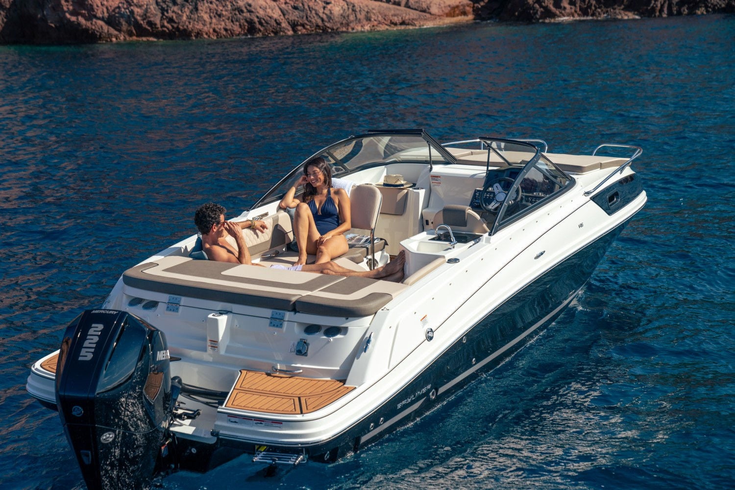 couple lounging on a VR6 Cuddy outboard overnight boat with the bimini up