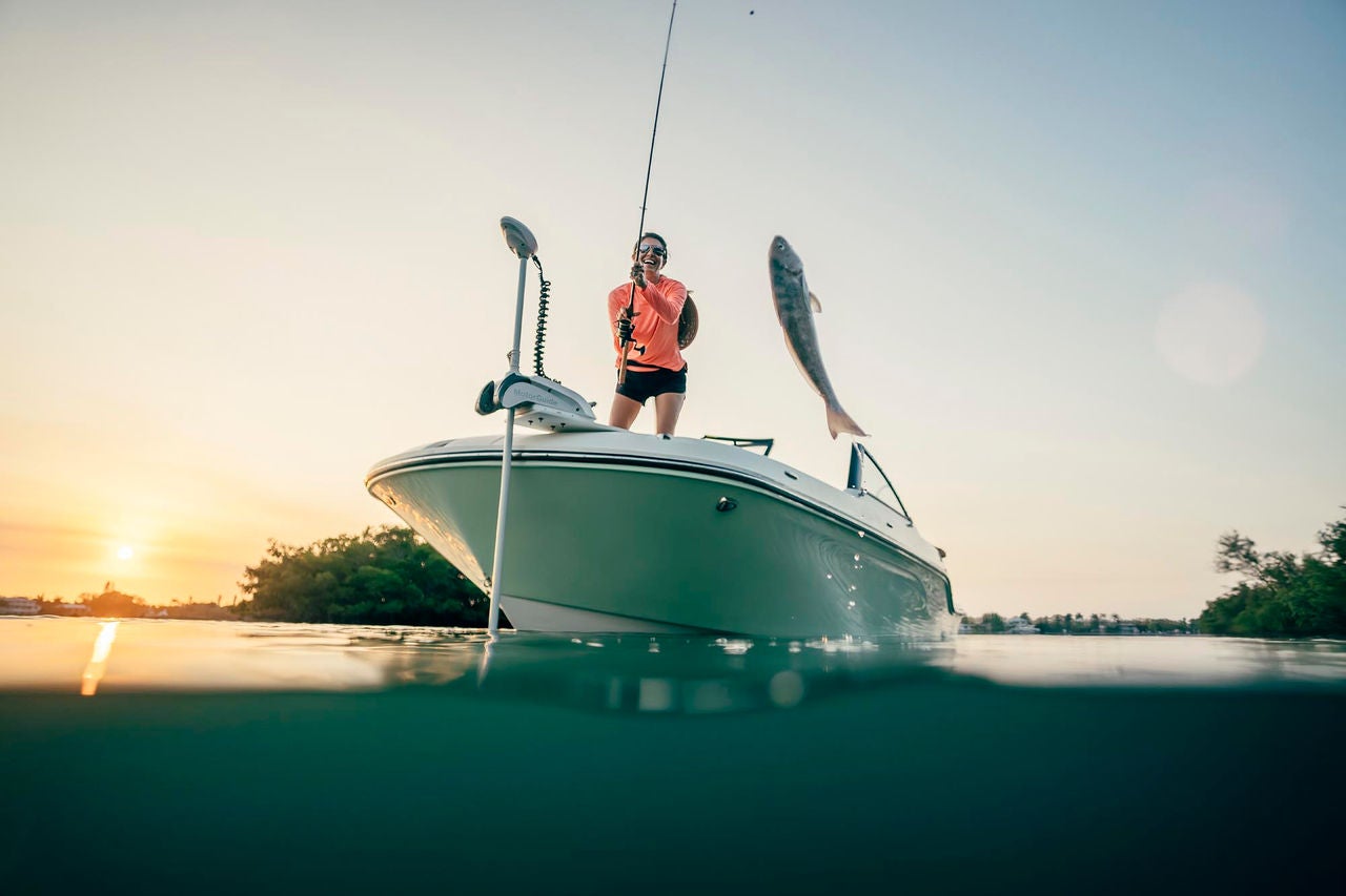 woman pulling a fish out of the water from the Trophy T22SC fishing boat