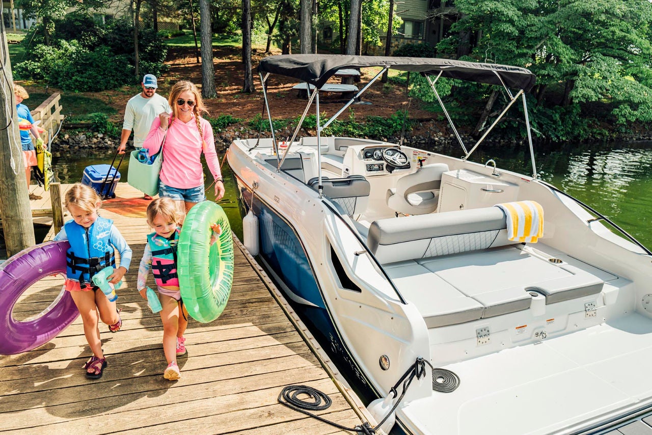 family walking on a dock towards their D22i deck boat