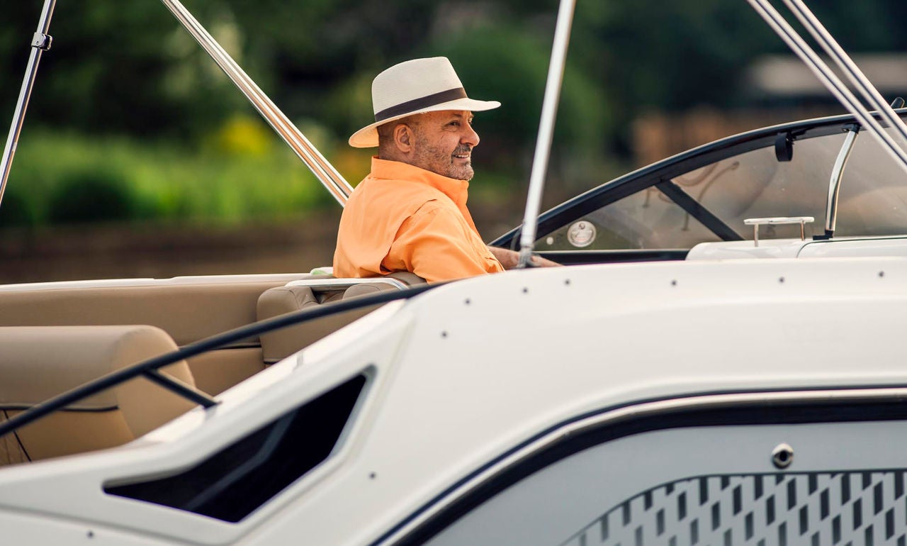 man sitting at the helm of the D22 deck boat