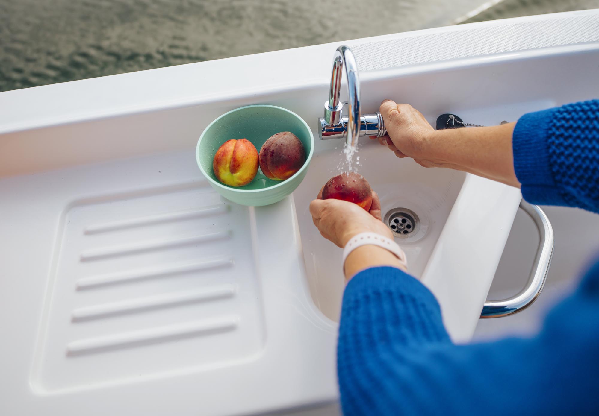 person washing fruit in the onboard sink on a D22 deck boat
