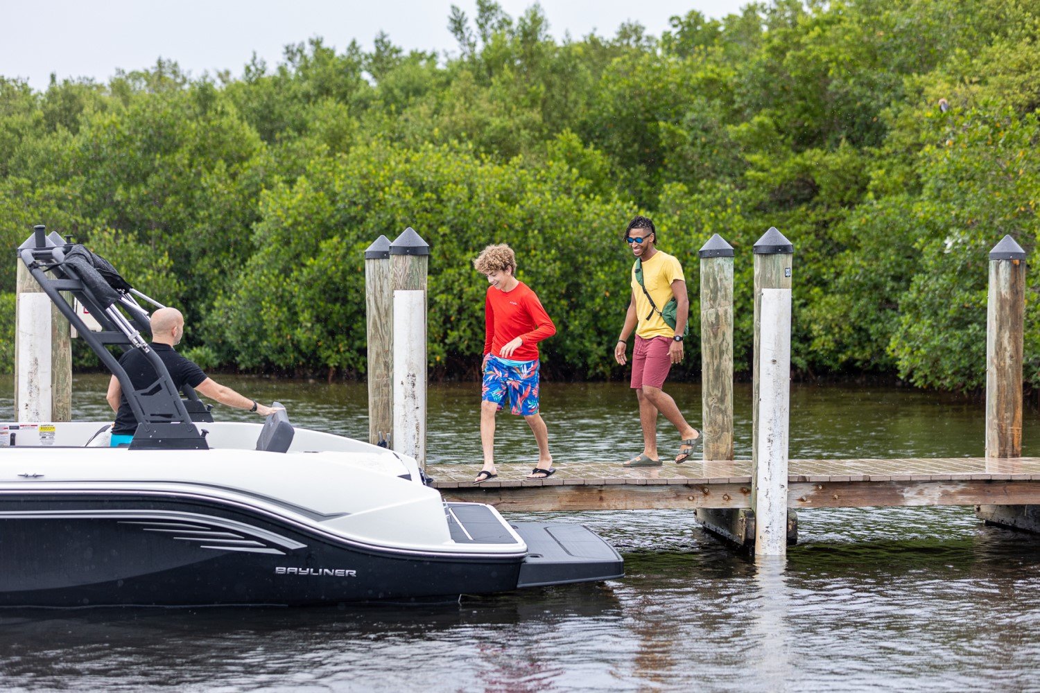 friends boarding a DX2050 deck boat next to a dock