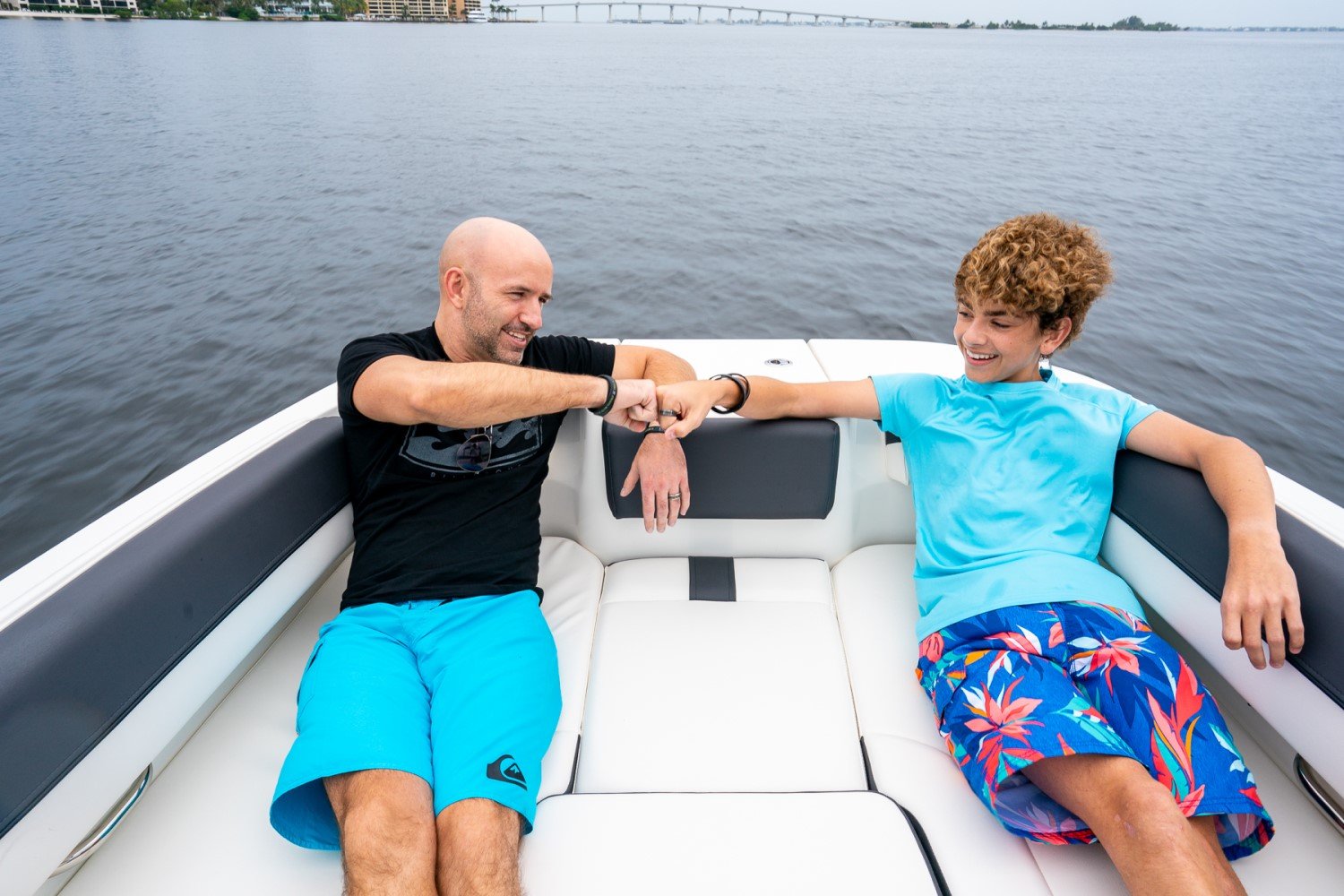 father and son sitting on the bow seats of the DX2050 deck boat